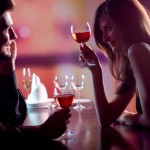 Young couple sharing a glass of red wine in restaurant, celebrat