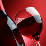 Still-life with bottle and glass of wine over red background